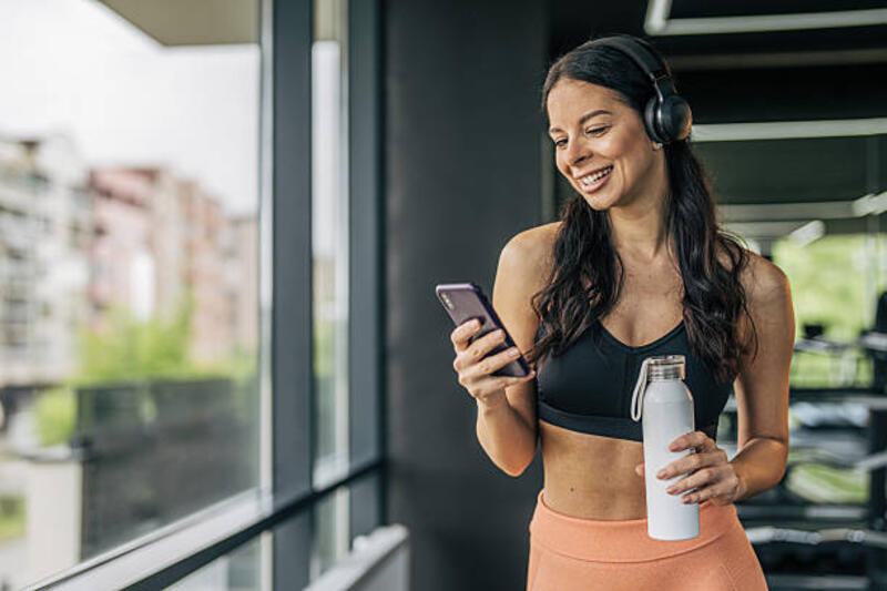 Olahragawan menggunakan smartphone dan mendengarkan musik di gym
