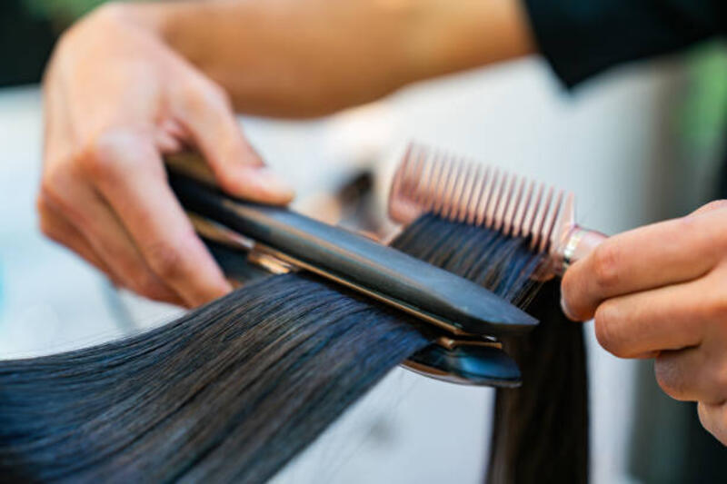 Close-up on a hairdresser straightening the hair of a woman at the hair salon Close-up on a hairdresser straightening the hair of a woman at the hair salon - beauty concepts hair straightener stock pictures, royalty-free photos &amp; images