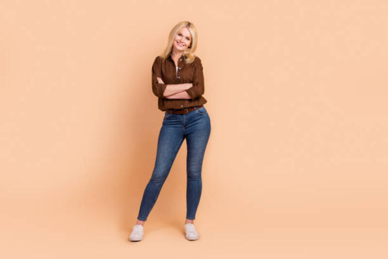 potret seluruh tubuh wanita paruh baya yang menawan, pekerja kantoran disilangkan, lengan disilangkan, kenakan pakaian kasual, latar belakang warna krem terisolasi; - skinny jeans potret stok, foto, &amp; gambar bebas royalti