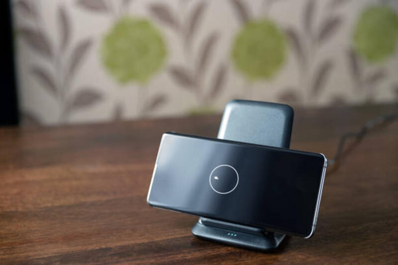 pengisian nirkabel smartphone pada dudukan pengisian daya di atas meja kayu