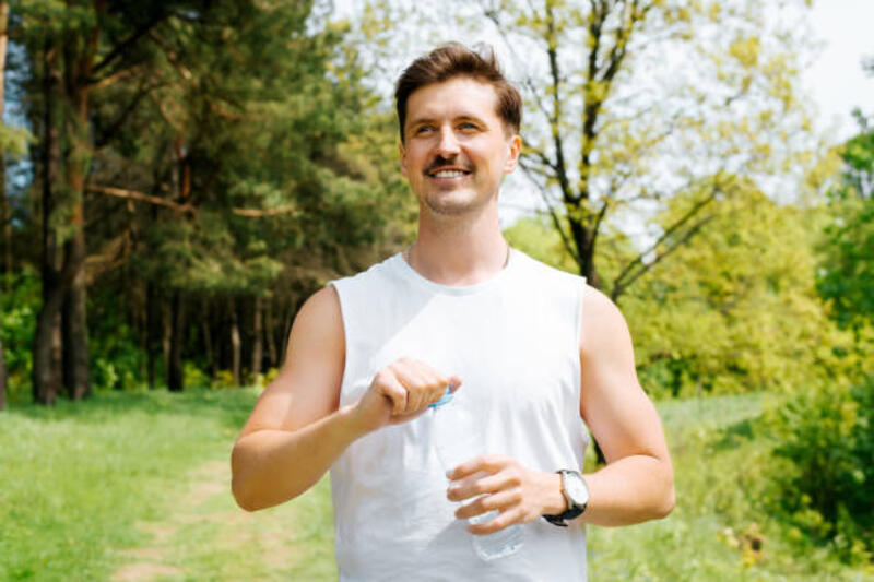 pemuda ceria dari penampilan eropa menikmati alam di luar ruangan dan memegang sebotol air. potret seorang pria atletik yang bahagia melihat ke samping. konsep rekreasi - sleeveless tshirt potret stok, foto, &amp; gambar bebas royalti