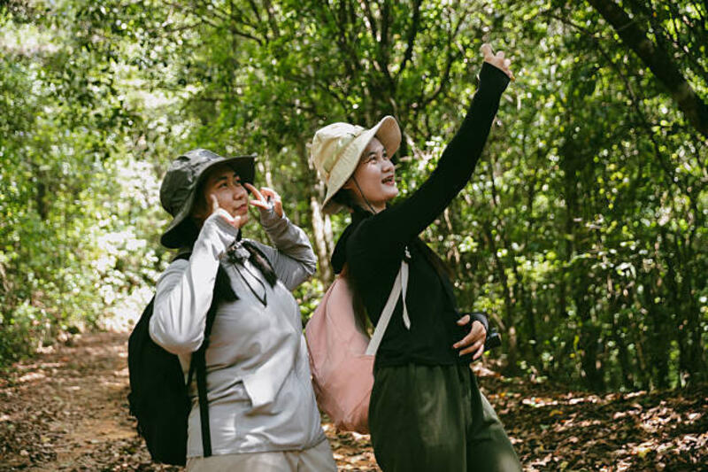 Dua teman wanita dengan ransel saat liburan mendaki pedesaan bersama. Teman Asia gadis backpacker teman bepergian di hutan liar bersama. bahagia dan menikmati hari yang cerah saat hiking.