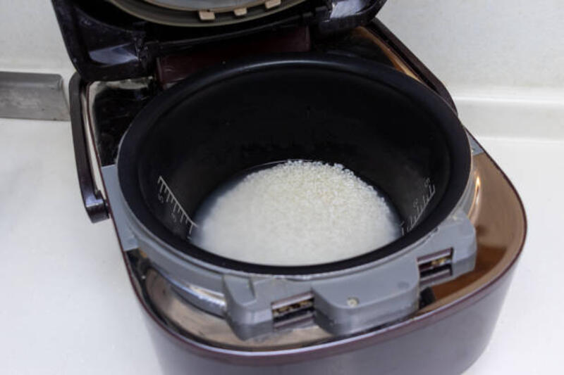 masak nasi dengan penanak nasi - memasukkan sayu ke rice cooker potret stok, foto, &amp; gambar bebas royalti