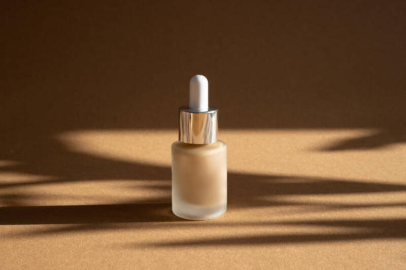 beige membuat fondasi dalam botol kaca mewah dengan latar belakang coklat. glamor make up masih hidup dengan bayangan gelap. latar belakang kosmetik feminin. - serum foundation potret stok, foto, &amp; gambar bebas royalti