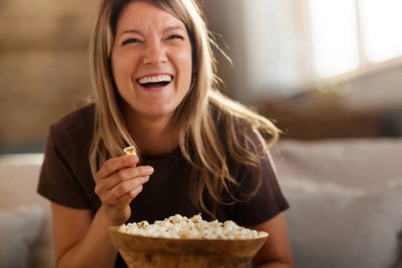 wanita ceria menonton film lucu di tv di rumah. - popcorn potret stok, foto, &amp; gambar bebas royalti