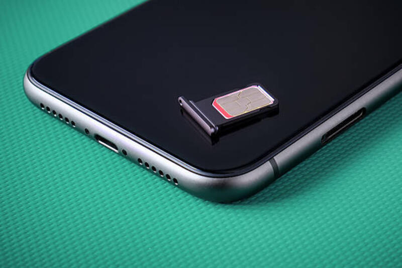 Kartu sim tergeletak di smartphone gelap. Mengganti kartu SIM untuk smartphone.