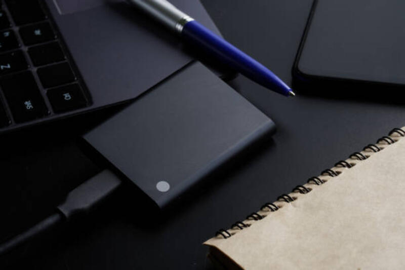 disk ssd portabel eksternal pada latar belakang hitam di samping laptop, smartphone, notepad dan pena. solid state drive. konsep teknologi modern, gadget dan penggunaan disk ssd - portable ssd potret stok, foto, & gambar bebas royalti