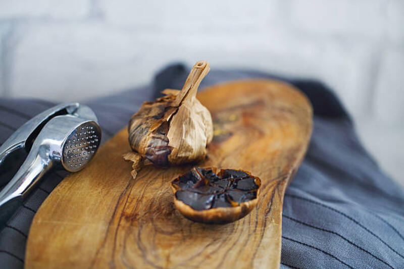 umbi bawang putih hitam dan siung di latar belakang kayu - black garlic potret stok, foto, &amp; gambar bebas royalti