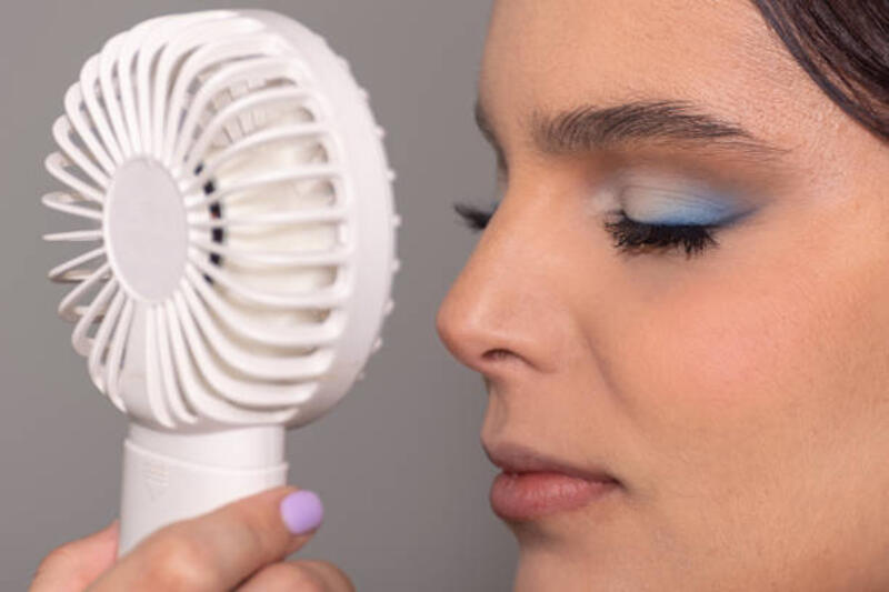 wanita muda menyegarkan dirinya dengan kipas angin kecil di hari musim panas - make up dengan kipas kecil potret stok, foto, & gambar bebas royalti