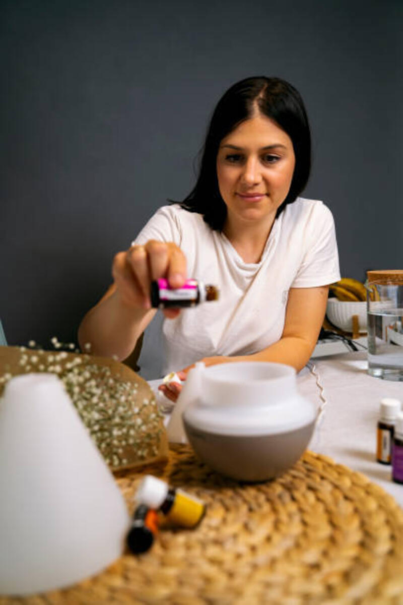 Wanita muda memegang botol minyak esensial dan meneteskan diffuser. persiapan aroma terapi
