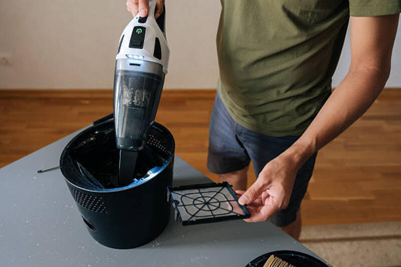 bidikan closeup pelembab udara pembersih pria dengan penyedot debu genggam, dengan hati-hati menghilangkan debu dari filter dan komponen internal untuk meningkatkan kualitas udara rumah. - vacuum cleaner filter potret stok, foto, & gambar bebas royalti