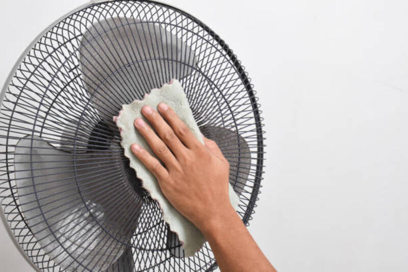 Tutup tangan memegang kain untuk membersihkan bagian kotor dan debu pada kipas angin