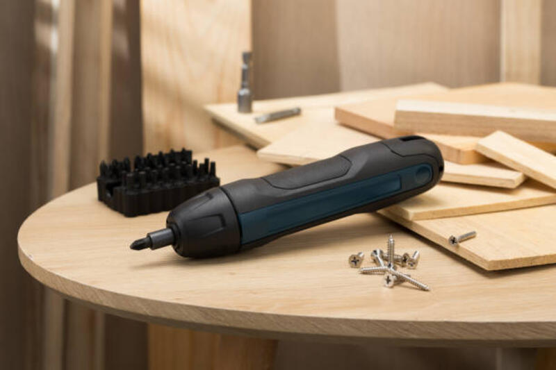 The image showcases a mini handheld cordless screwdriver, ideal for quick DIY tasks. The image features a mini handheld cordless screwdriver, surrounded by various screws and wooden planks, highlighting its utility in DIY projects and home repairs. mini electric screwdrivers stock pictures, royalty-free photos &amp; images