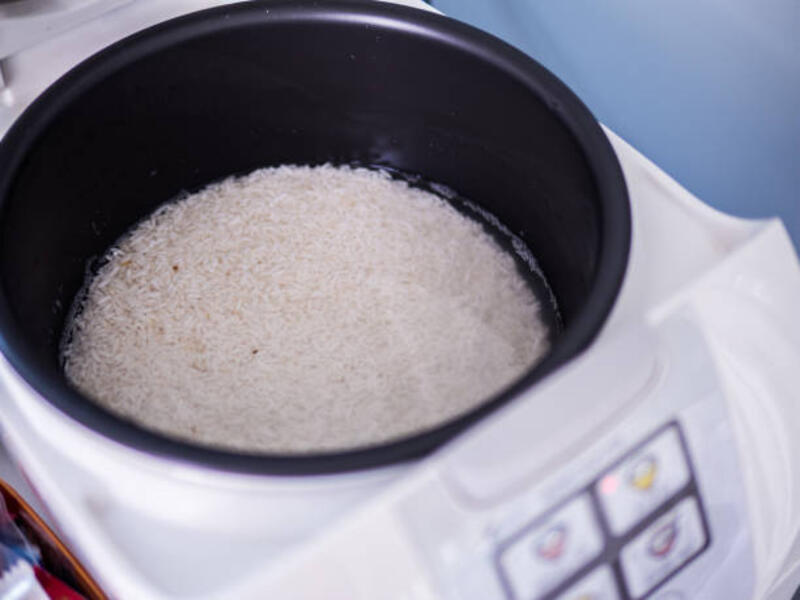 nasi mentah dalam kompor elektronik, cahaya di bagian bawah masak selama pengukusan. - rice cooker pot potret stok, foto, &amp; gambar bebas royalti