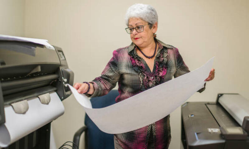 Senior silver-haired woman, engeneer, using the commercial wide format printer Senior silver-haired woman, engeneer, using the commercial wide format printer in the office. plotter printer stock pictures, royalty-free photos &amp; images