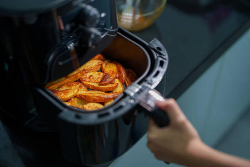 a woman is using an air fryer to prepare food in her kitchen, focusing on a healthier cooking method with minimal oil. - oven listrik potret stok, foto, &amp; gambar bebas royalti