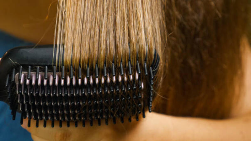 close-up seorang wanita menyisir dan mengeringkan rambutnya dengan pelurus rambut elektrik - heated comb potret stok, foto, &amp; gambar bebas royalti