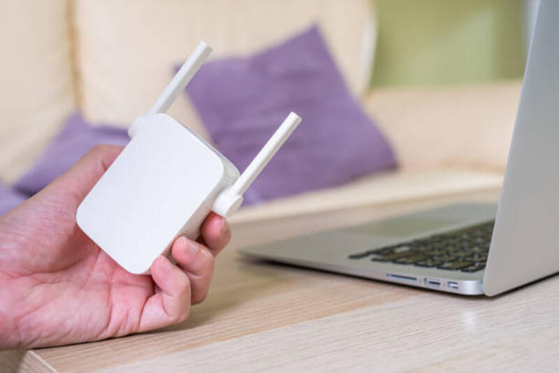 fokus selektif pada range extender. router internet di meja kerja dengan pria kabur menghubungkan kabel di latar belakang. koneksi internet cepat dan berkecepatan tinggi untuk mencakup penggunaan jaringan rumah. - wifi range extender potret stok, foto, &amp; gambar bebas royalti