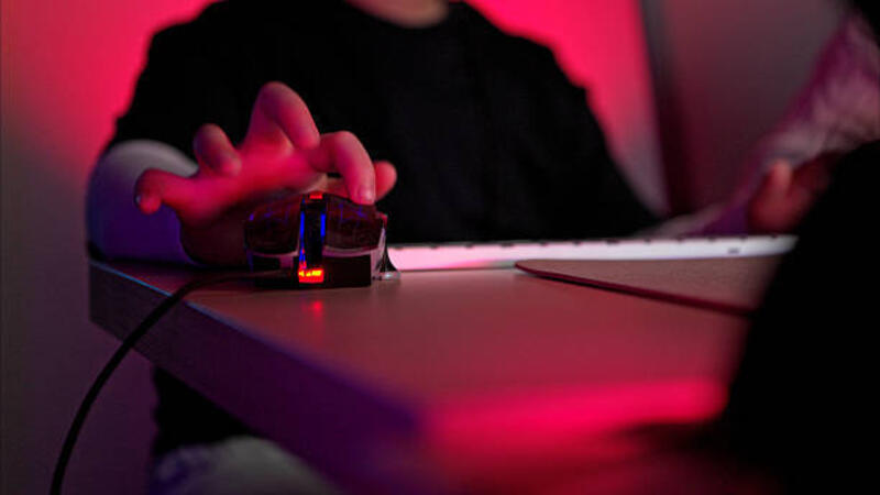close-up seseorang menggunakan mouse gaming dengan pencahayaan rgb di sebelah keyboard di ruangan gelap dengan lampu merah neon - gaming mouse potret stok, foto, & gambar bebas royalti