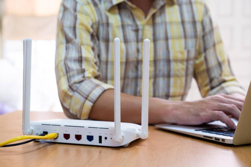 fokus selektif pada router. router internet di meja kerja dengan pria kabur menggunakan tablet di latar belakang. koneksi internet cepat dan berkecepatan tinggi dari jalur fiber dengan koneksi kabel lan. - router settings potret stok, foto, & gambar bebas royalti