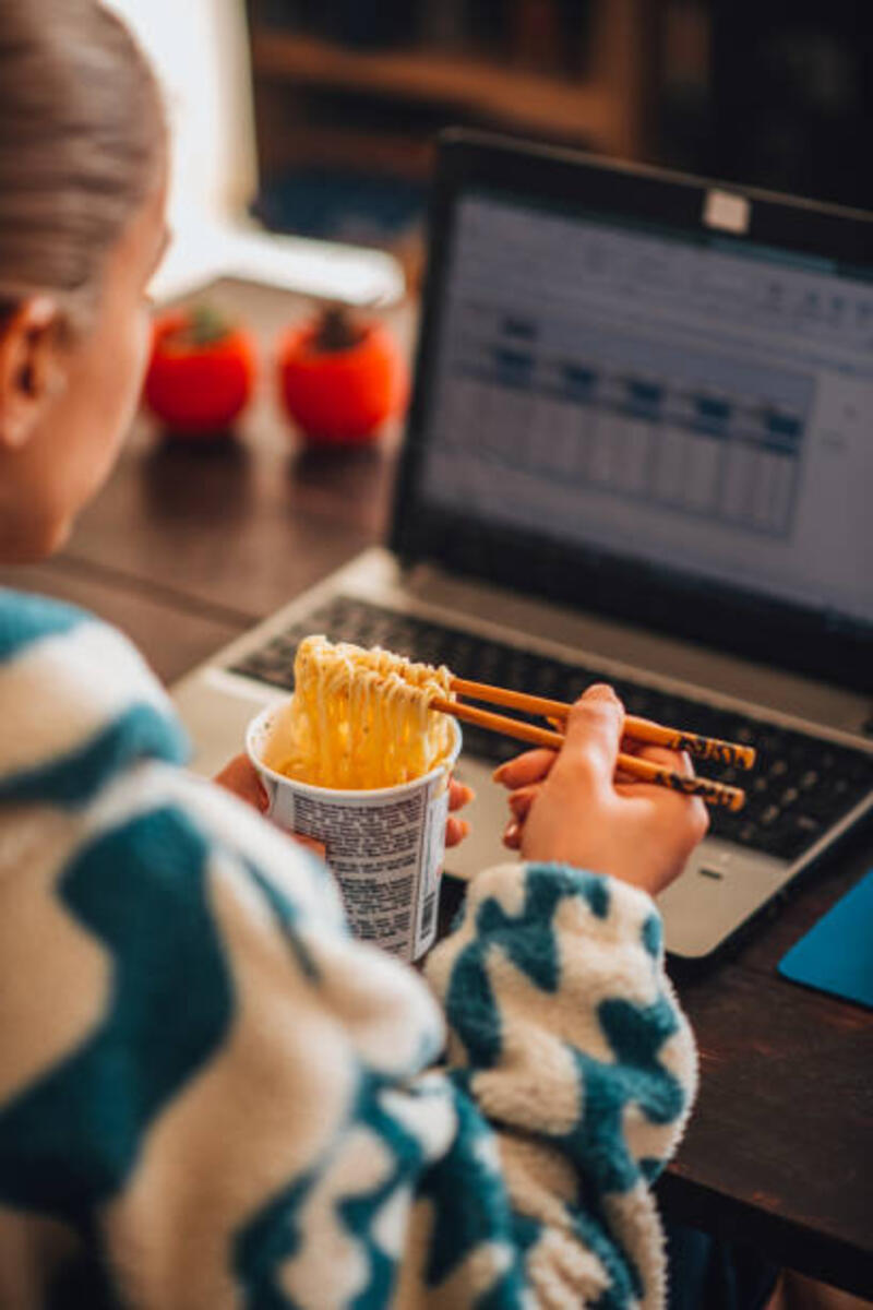 Wanita yang Bekerja dari Rumah Makan Mie di Depan Komputer