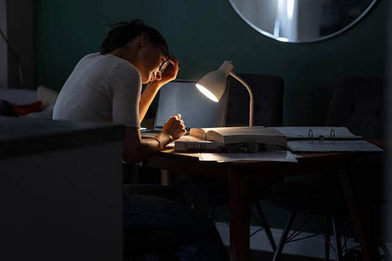 Female Studying Hard at Nighttime Medium side-view shot of a mid-adult female studying at the kitchen table in her home in Newcastle upon Tyne, North East England. She is wearing glasses and leaning her head in one hand, the table covered with books, files and a laptop, illuminated by lamplight.

Videos similar to this scenario available. desk lamp stock pictures, royalty-free photos &amp; images