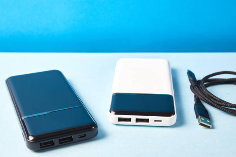power bank untuk mengisi daya perangkat seluler. pengisi daya putih dan hitam dengan kabel. baterai eksternal untuk perangkat seluler. - powerbank 10000 mah potret stok, foto, &amp; gambar bebas royalti