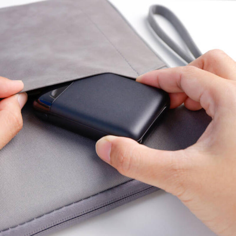 Close up tangan pria masukkan power bank ke dalam tas