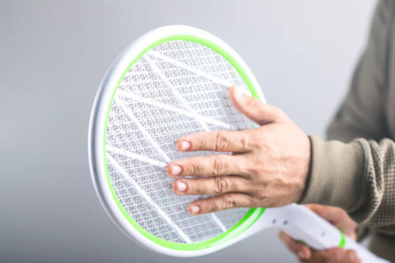 a man is holding the swatter and touching its circuit, whether it poses a physical danger to the human body. concept explores whether a person can touch the circuit of an electric mosquito swatter - menyentuh jaring raket nyamuk potret stok, foto, &amp; gambar bebas royalti