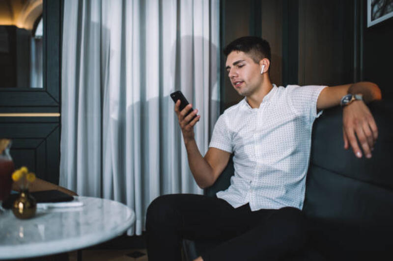 pria muda dengan smartphone dan earphone nirkabel sejati di kafe - tws potret stok, foto, &amp; gambar bebas royalti