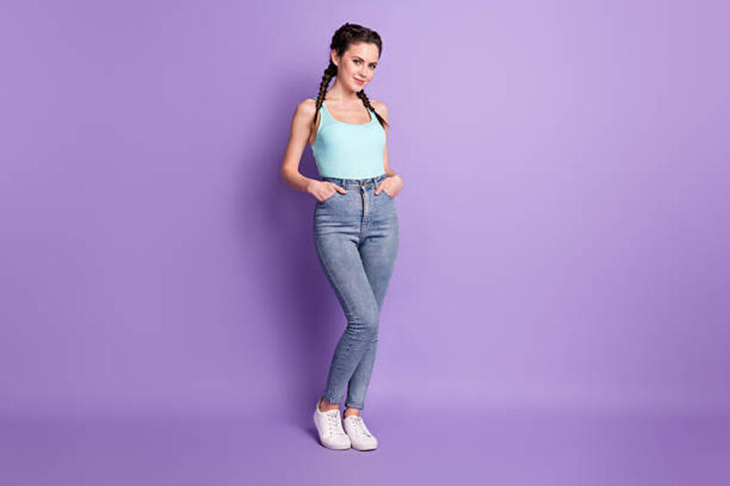 ukuran tubuh panjang penuh pemandangan gadis pemalu ceria yang menarik berpegangan tangan di saku terisolasi di atas latar belakang warna ungu ungu - skinny jeans potret stok, foto, &amp; gambar bebas royalti