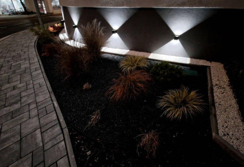 spot wall light illuminates the wall of facade of the house in a conical shape at night. evening positioning and navigation lamp of black color shines in two directions on the gabion wall, back yard - lampu taman dinding potret stok, foto, & gambar bebas royalti