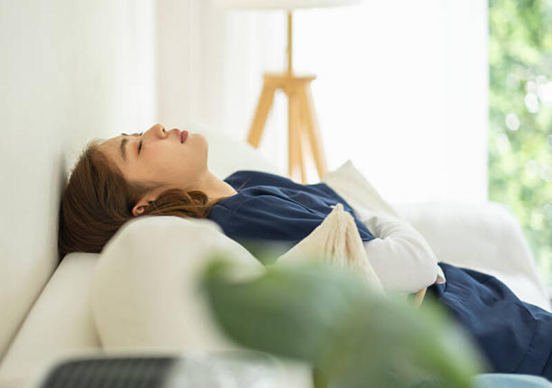 perawat wanita asia yang terlalu banyak bekerja dengan scrub biru berbaring telentang di sofa bersantai di ruang tamu di rumah beristirahat dari stres kerja dan kelelahan - tensi normal potret stok, foto, &amp; gambar bebas royalti