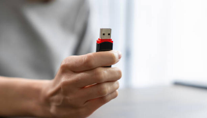 hand holding usb flash drive with connecting to laptop at wooden table - flashdisk potret stok, foto, & gambar bebas royalti